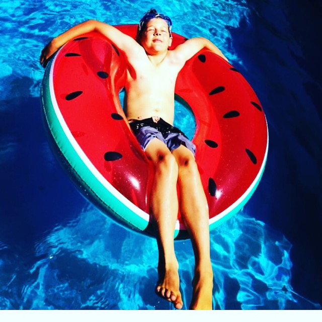 happy kid sunbathing on a watermelon pool float
